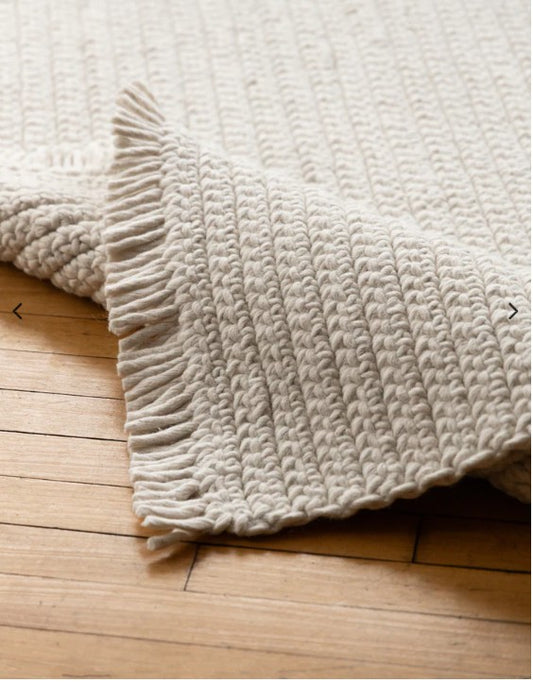 Textured beige blanket on a wooden floor