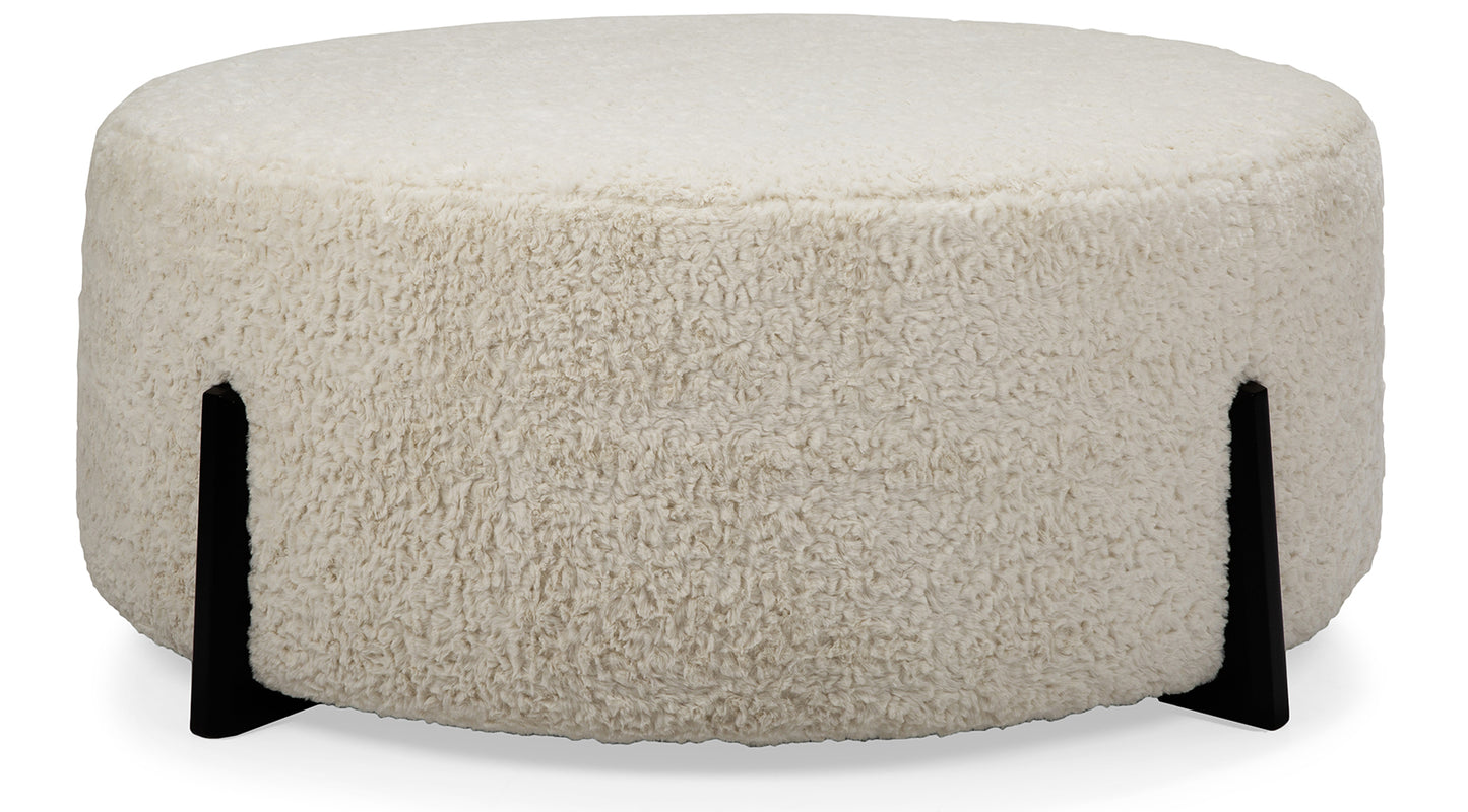 Round beige ottoman with black legs on a white background