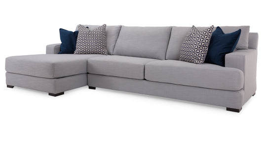 Gray sectional sofa with patterned and solid color cushions on a white background