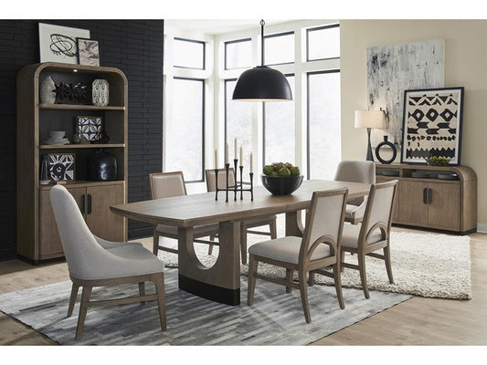 Dining room with wooden table and chairs, bookshelf, and large windows.