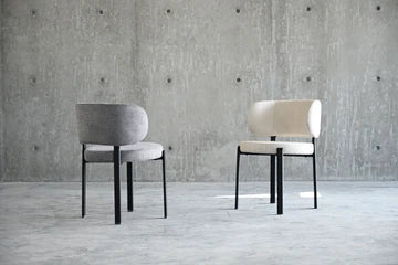 Two modern chairs against a concrete wall.