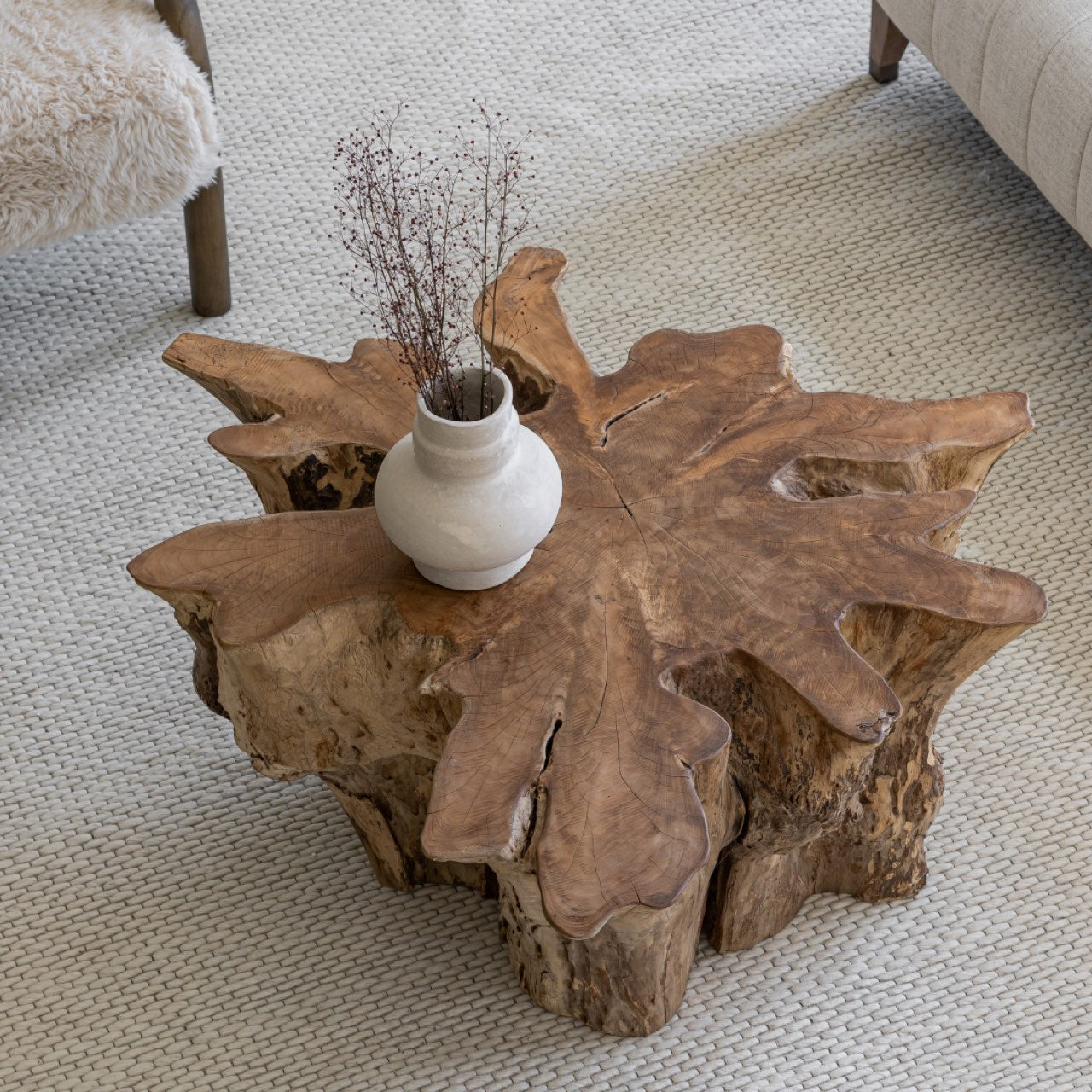 Wooden coffee table with a vase of dried plants on a carpeted floor.