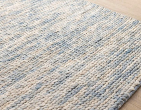 Textured blue and beige rug on a wooden floor