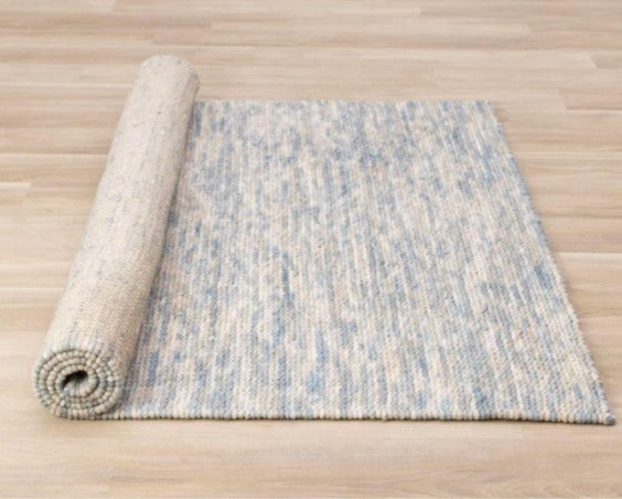 Rolled-up blue and beige patterned rug on a wooden floor