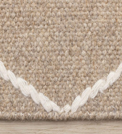 Close-up of a textured beige carpet with white border