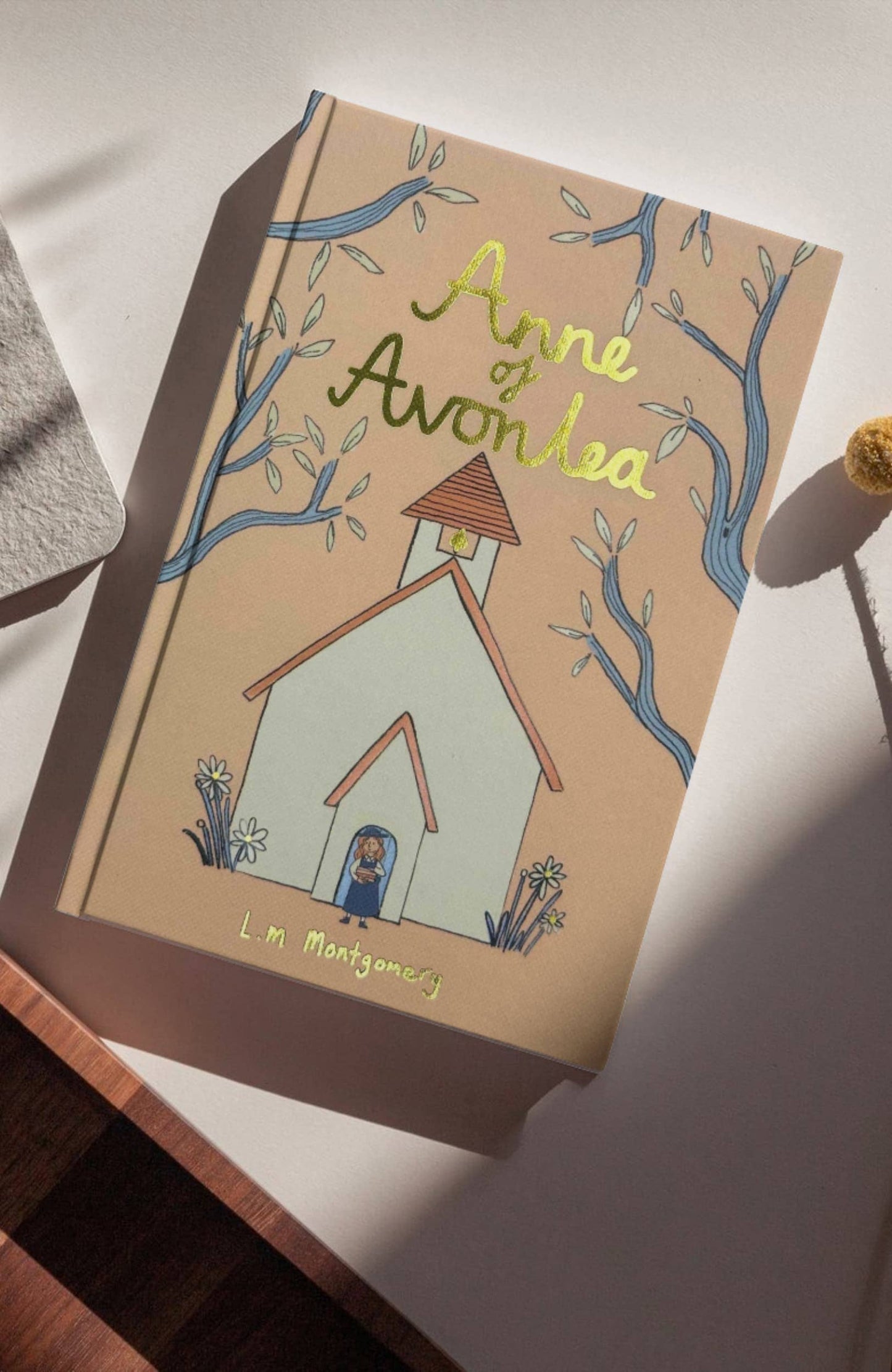 Book titled 'Anne of Avonlea' by L.M. Montgomery on a white surface with a wooden edge.