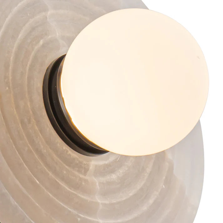 Close-up of a light fixture with a spherical bulb on a textured beige background