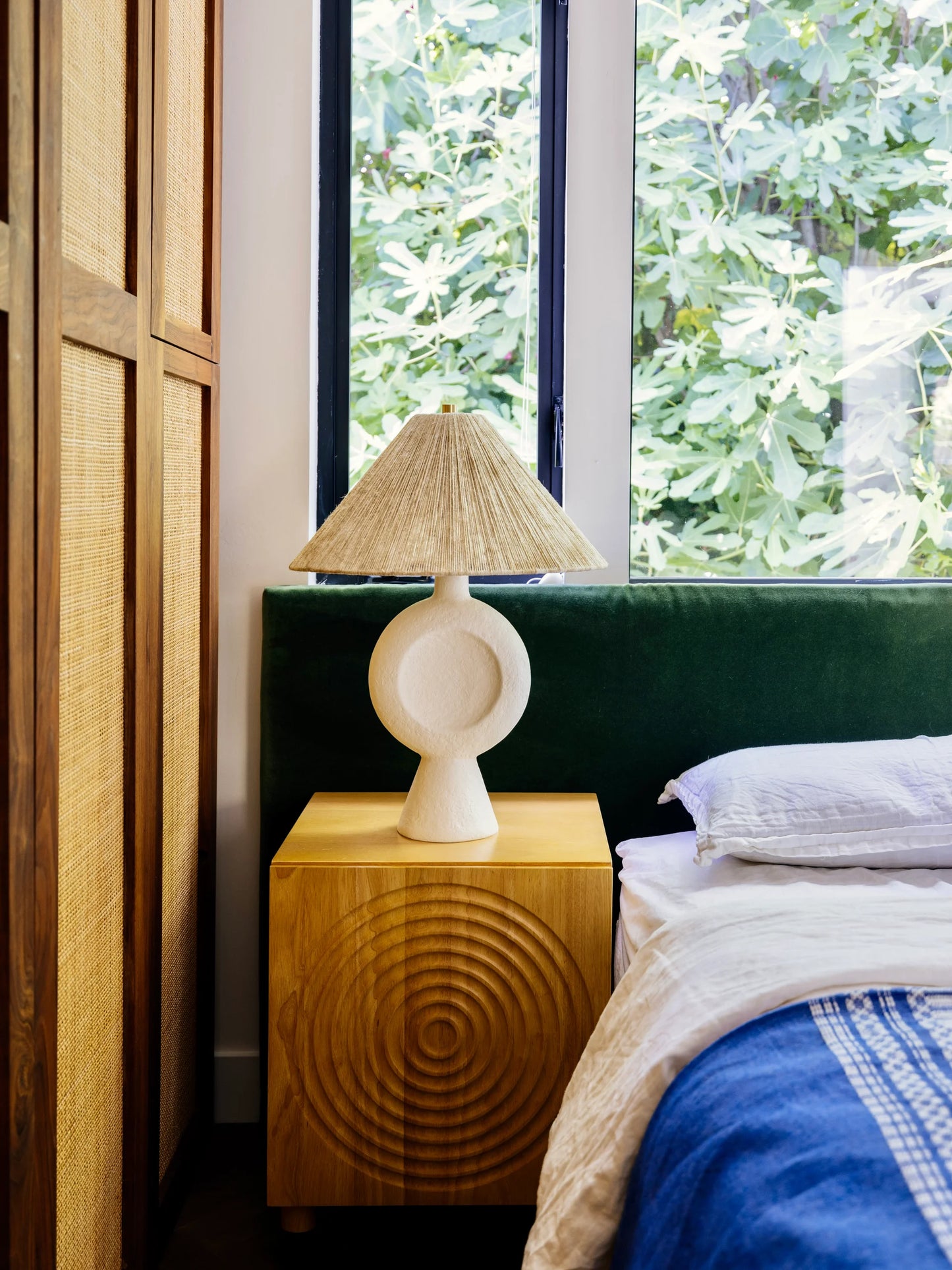 Bedroom with wooden nightstand, lamp, and green headboard.