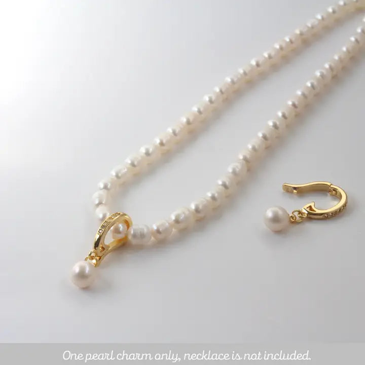 Pearl charm with gold clasp on a white background