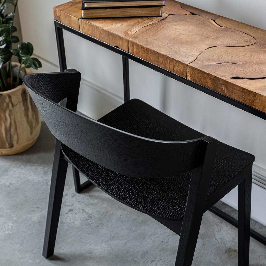 Black chair with woven seat next to a wooden table in a room setting.