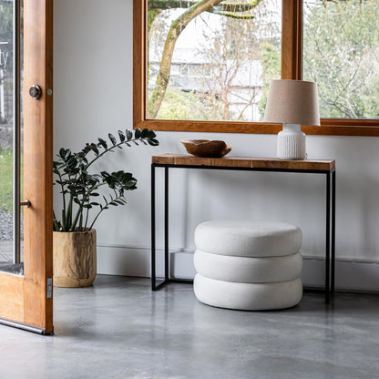 Modern interior with a white ottoman, console table, and plant near a glass door.
