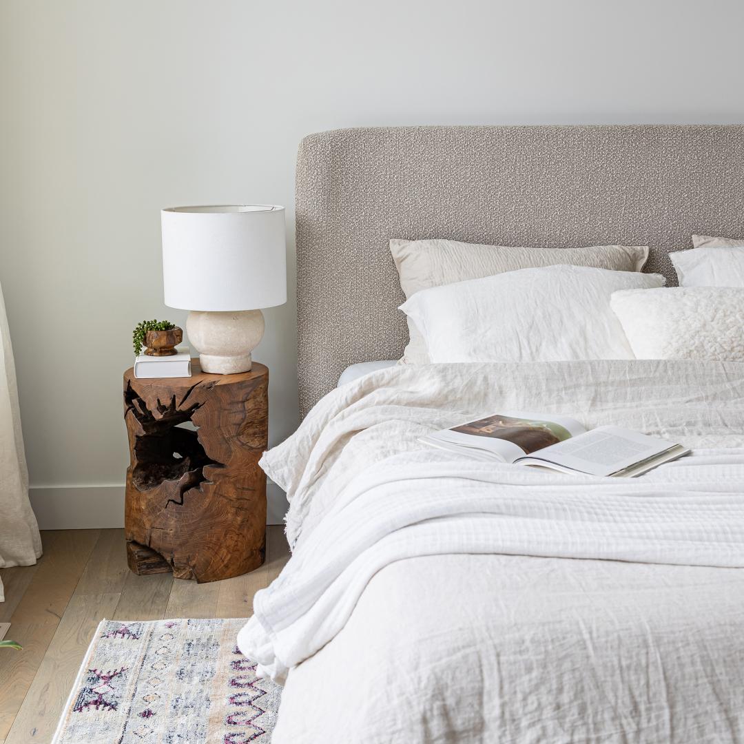 Bedroom with a bed, nightstand, and lamp in a neutral color scheme.