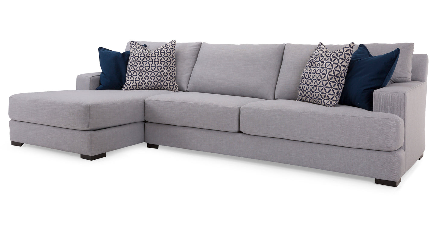 Gray sectional sofa with patterned and solid color cushions on a white background