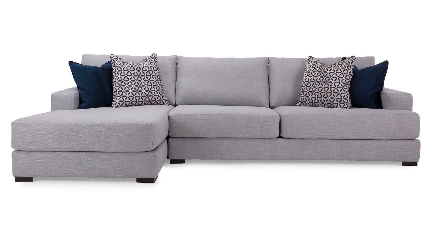 Gray sectional sofa with patterned and solid blue pillows on a white background