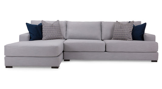 Gray sectional sofa with patterned and solid blue pillows on a white background