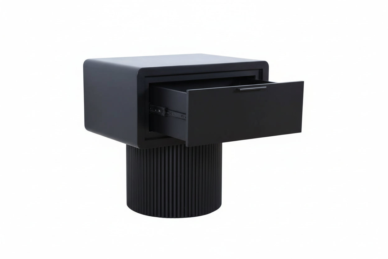 Black side table with a drawer on a wooden floor against a white wall