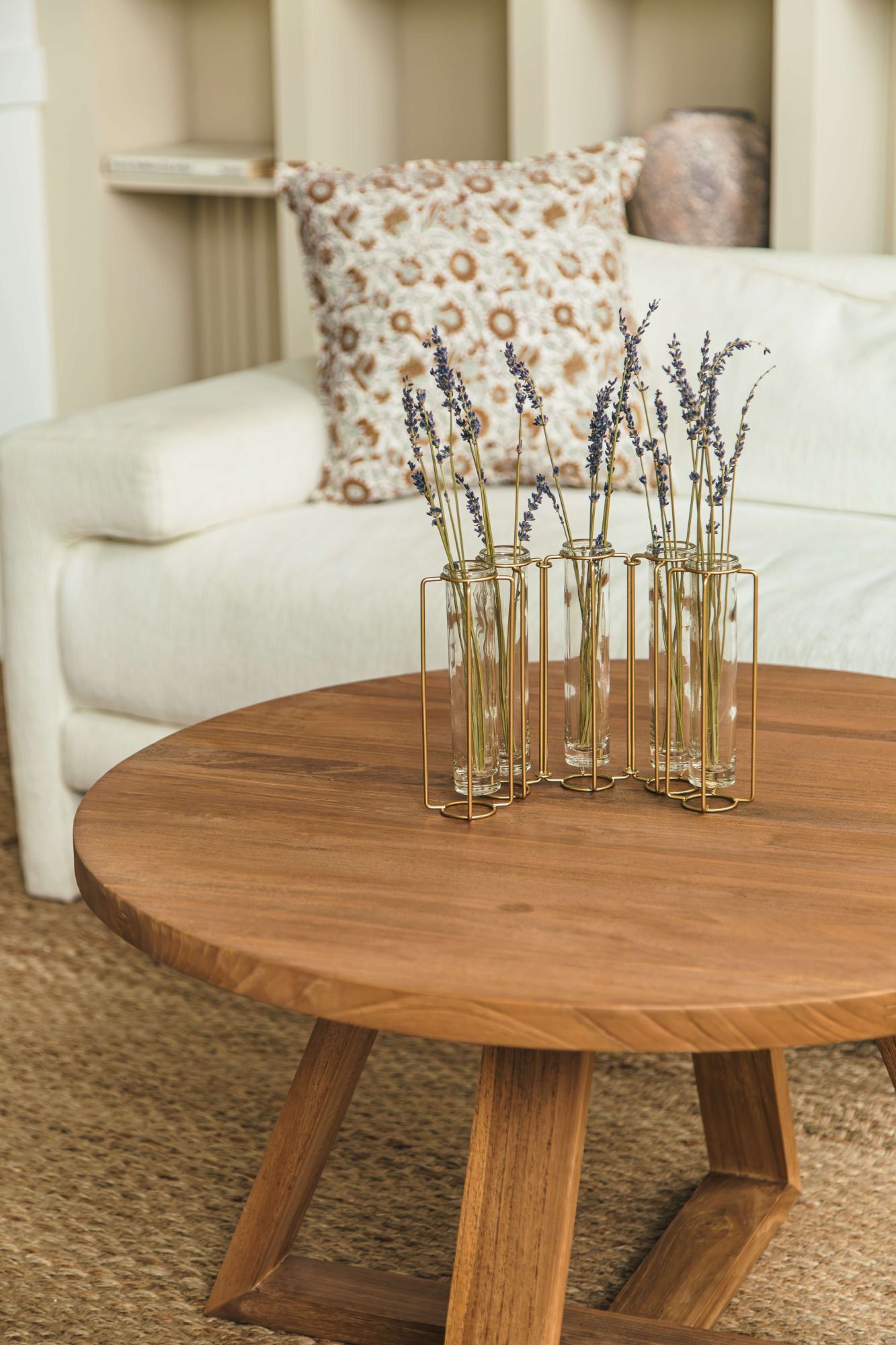 Wooden coffee table with decorative vases and flowers in a living room setting.