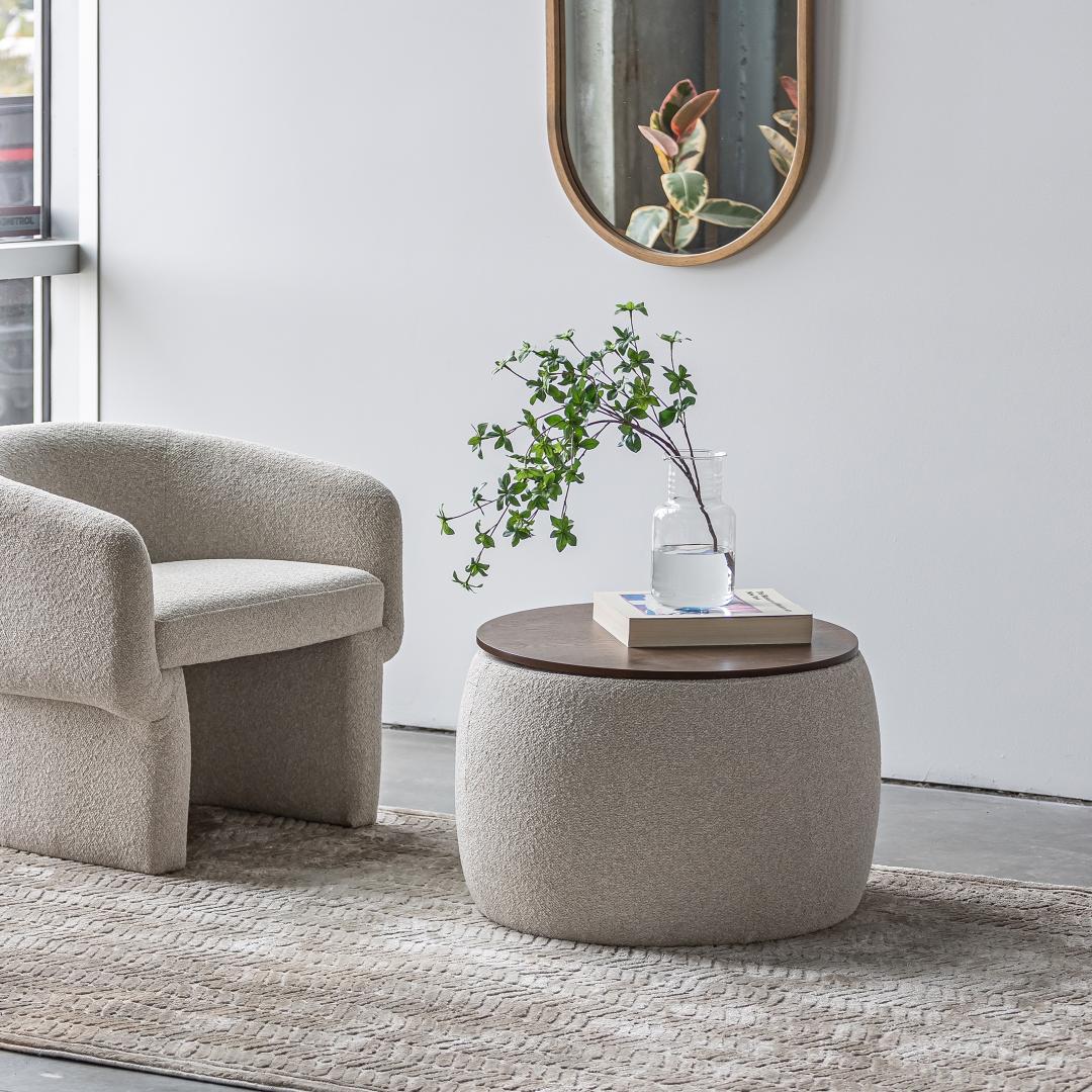 Modern living room with a beige armchair and round ottoman table.