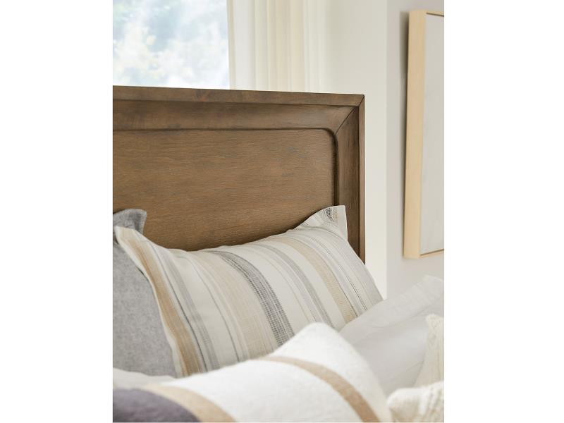 Wooden headboard with striped pillows against a neutral wall.