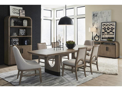 Dining room with wooden table and chairs, bookshelf, and large windows.