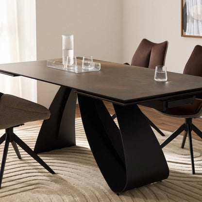 Modern dining table with black legs and brown chairs in a room with light-colored walls and wooden floor.