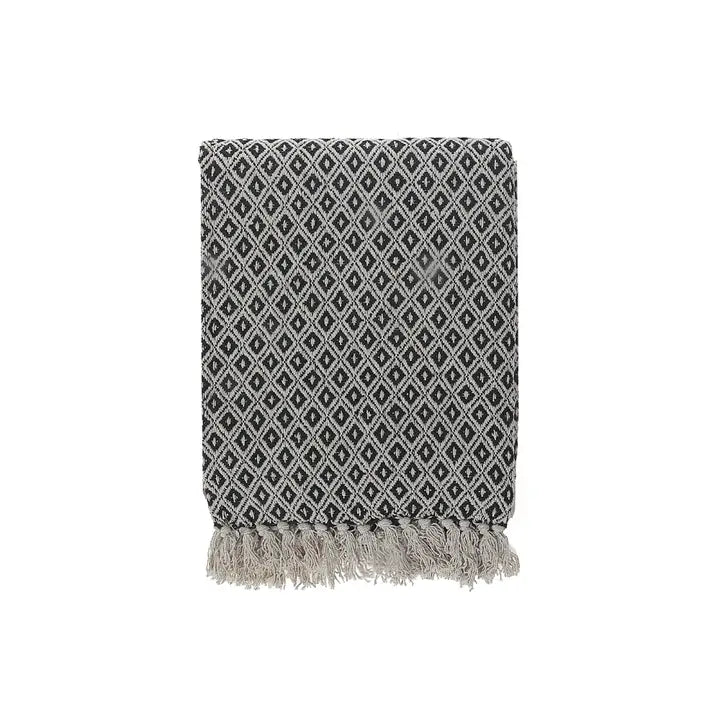 Black and white patterned throw blanket with fringes on a white background