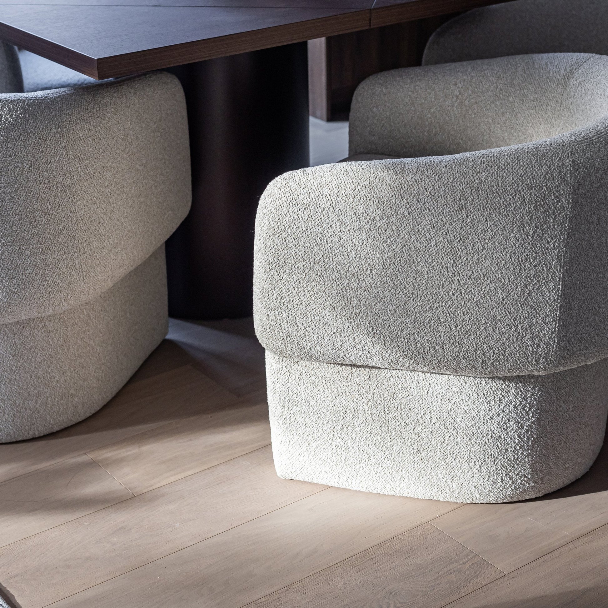 Textured gray chairs in a room with a wooden floor and table.