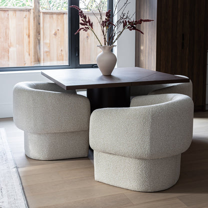 Two beige chairs around a wooden table with a vase of flowers in a modern room.