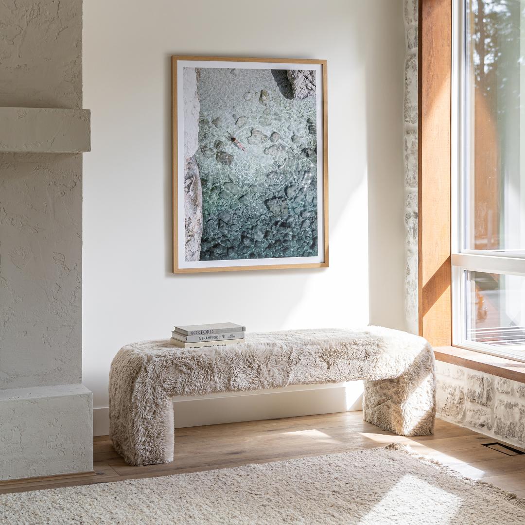 Modern living room with a textured bench, abstract art, and large window.