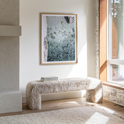 Modern living room with a textured bench, abstract art, and large window.