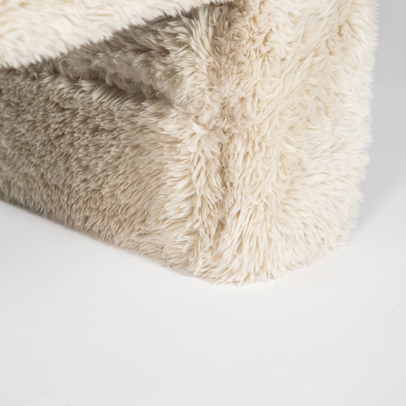 Close-up of a fluffy beige blanket on a light gray background