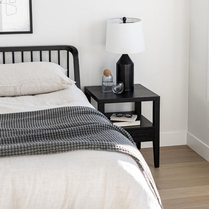 Bedroom with a black nightstand, lamp, and decor items.