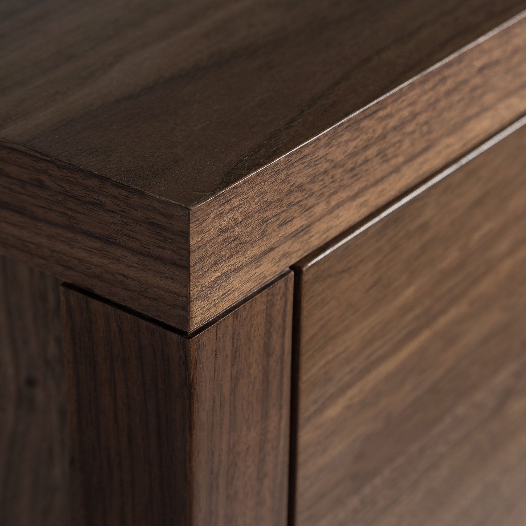 Close-up of a wooden cabinet corner with a focus on the grain and finish.