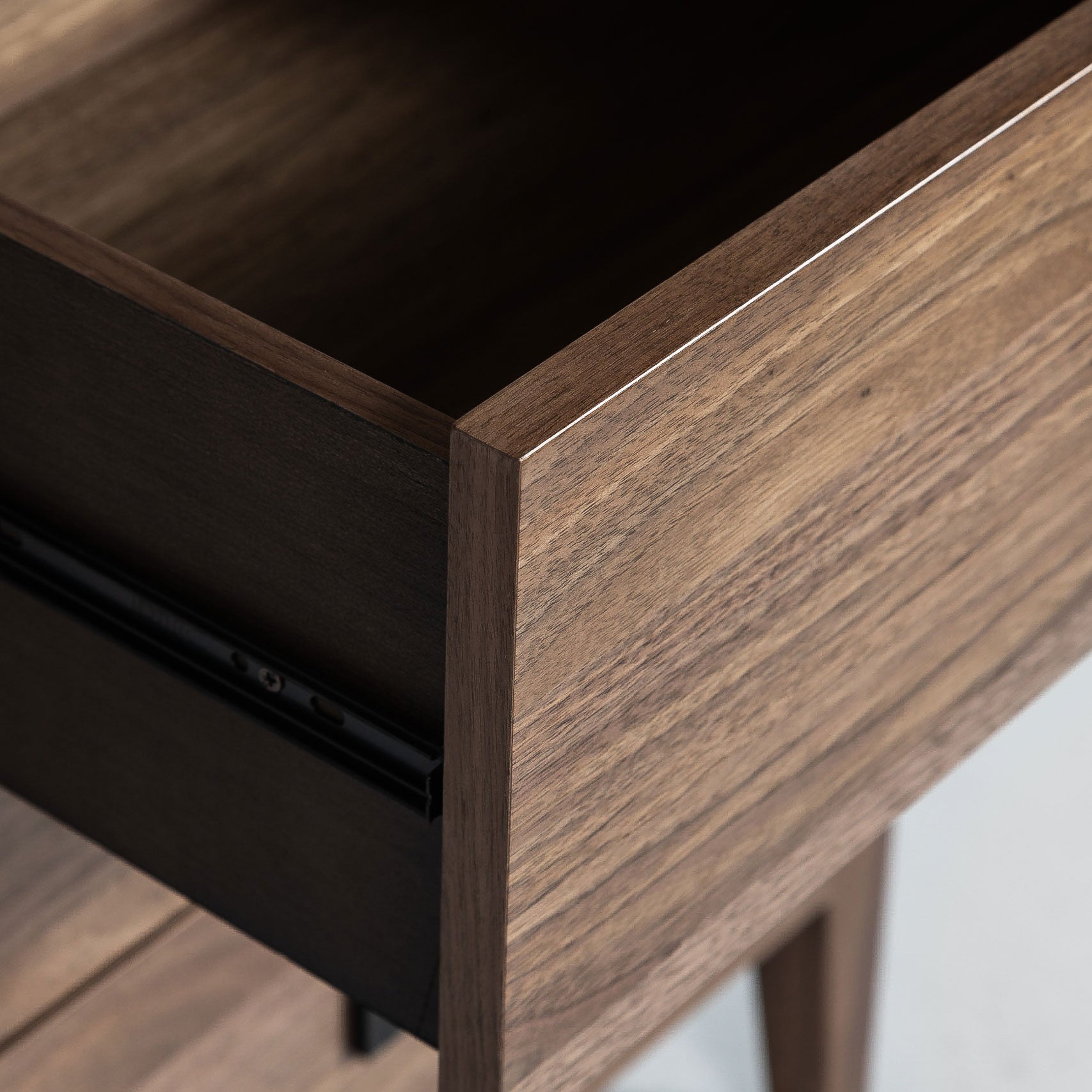 Close-up of a wooden desk corner with a black surface.