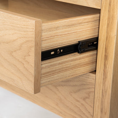 Wooden drawer with metal slide mechanism on a light wood cabinet.