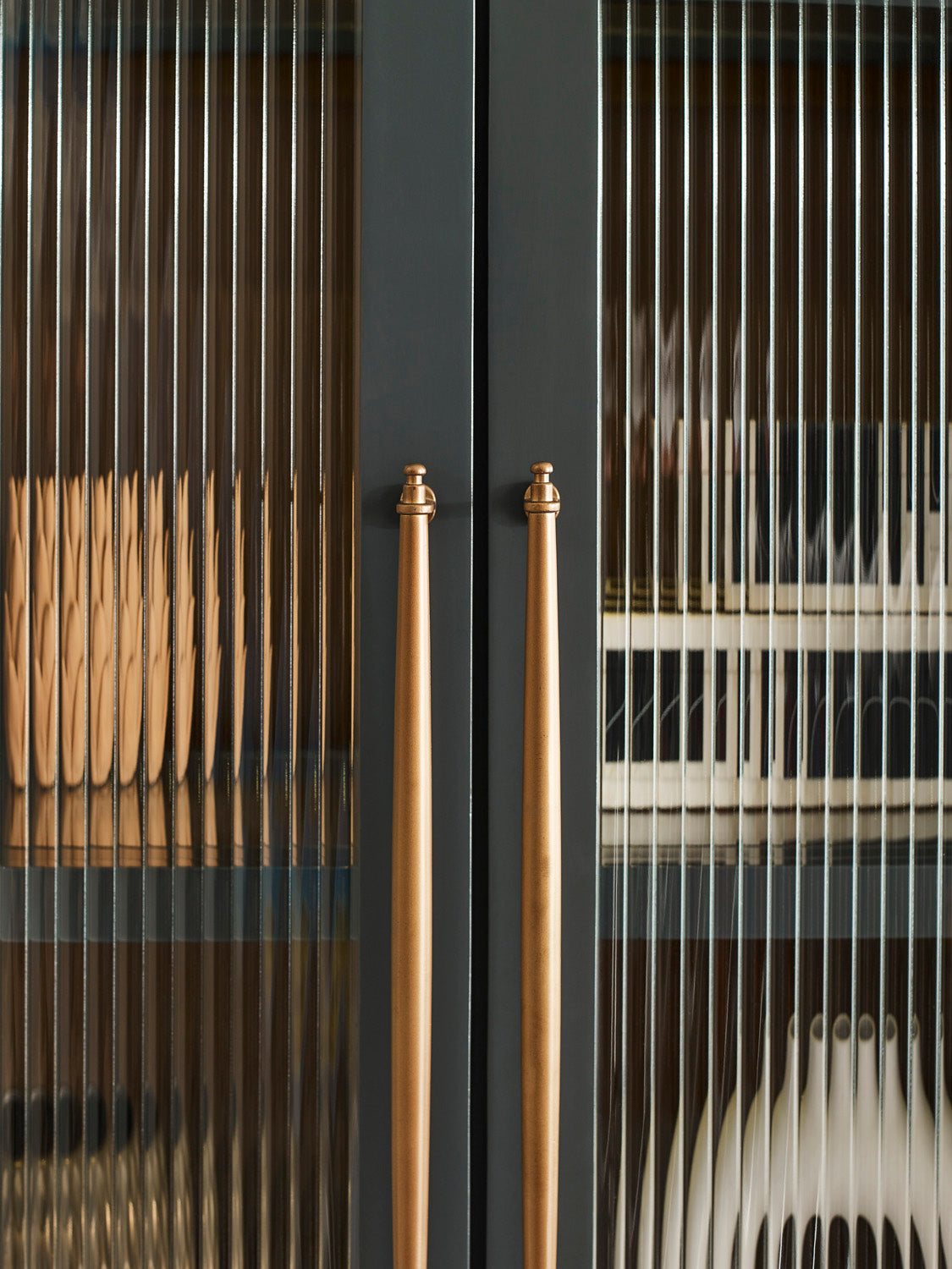 Close-up of a black cabinet with gold handles and glass panels.