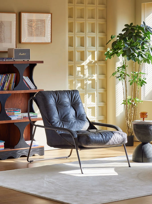 Modern black armchair in a living room with a bookshelf and decorative elements.