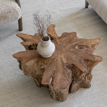 Wooden coffee table with a vase of dried plants on a carpeted floor.
