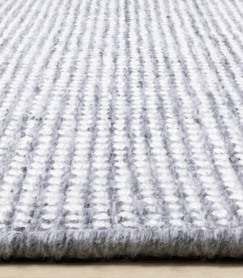 Close-up of a textured gray and white rug on a wooden floor.