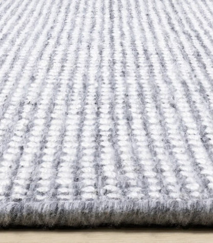 Close-up of a textured gray and white rug on a wooden floor.