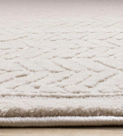 Close-up of a textured beige rug with a diamond pattern on a light wooden floor.