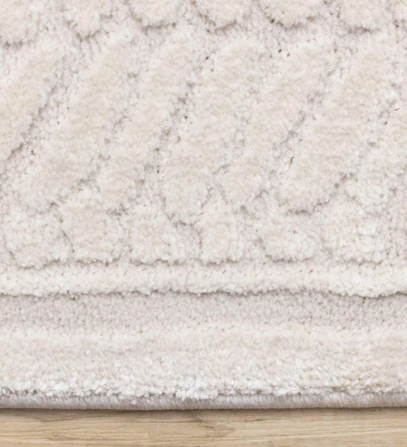 Close-up of a textured beige rug on a wooden floor