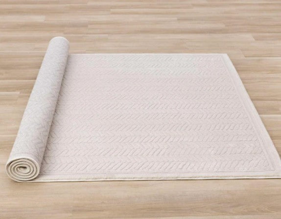 Rolled-up white bath mat on a wooden floor