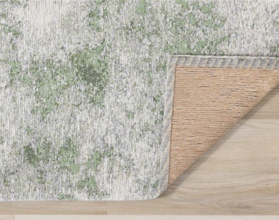 Textured green and beige rug on a wooden floor