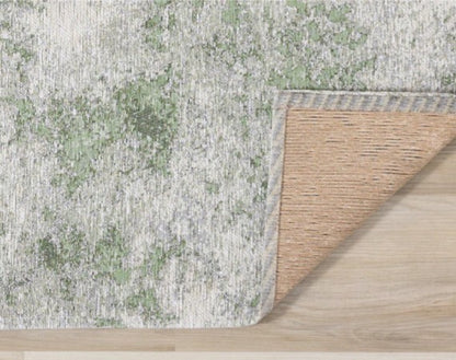 Textured green and beige rug on a wooden floor