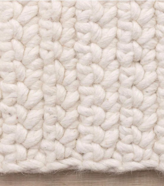 Close-up of a textured white rug on a wooden floor