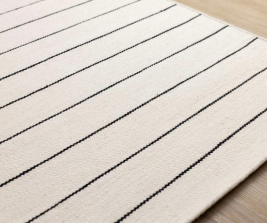 Beige rug with black stripes on a wooden floor