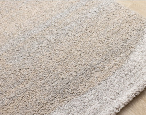 Beige and white gradient rug on a wooden floor