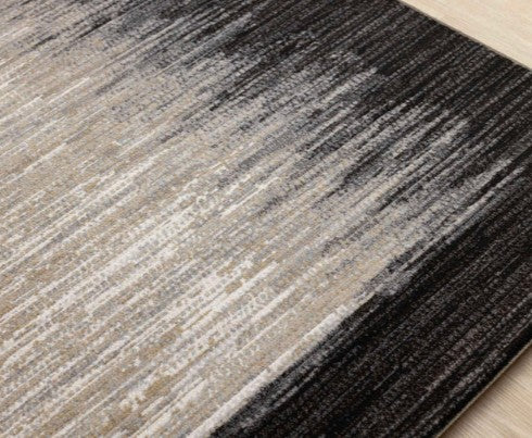 Close-up of a textured area rug with gradient colors on a wooden floor.