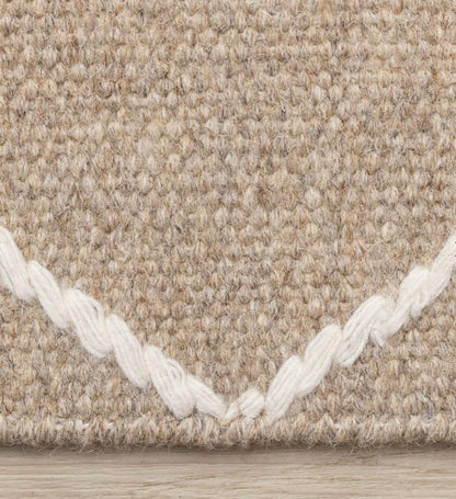 Close-up of a textured beige carpet with white border